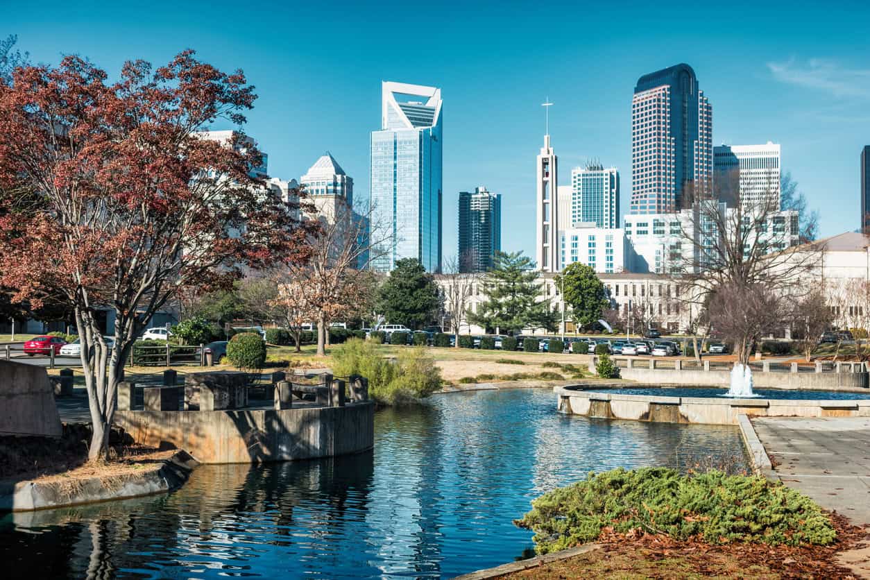 Charlotte North Carolina Audio and Visual Solutions Install and Maintain  drive-thru technology A city park with a pond and fountain in the foreground, trees on the left, and modern skyscrapers in the background under a clear blue sky.