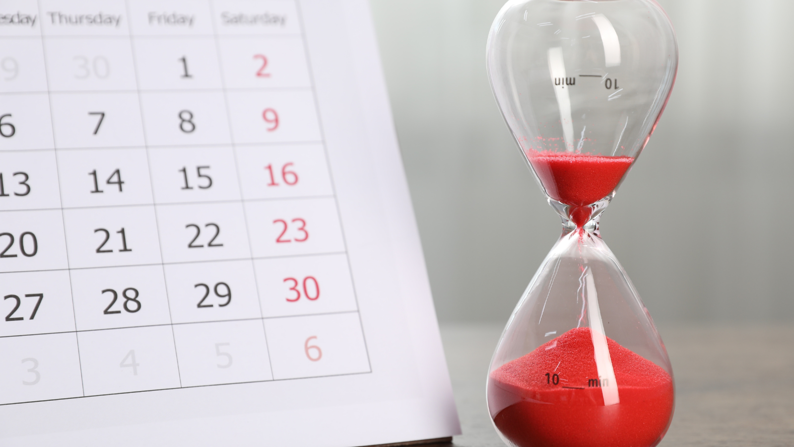 A calendar showing dates and an hourglass with red sand partially drained, symbolizing time passing or a deadline approaching&mdash;perfect imagery for the fast-paced demands of commercial WiFi QSR restaurant infrastructure.